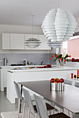 Designer lampshades and dining table in modern, open-plan kitchen