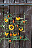 Wall hanging with roses and Chinese reed: Wreaths made of petals and Chinese reed, lampion fruits as decoration