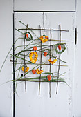 Wall hanging with roses and Chinese reed: Wreaths made of petals and Chinese reed, lampion fruits as decoration