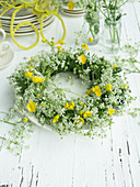 Wreath of cow parsley and buttercups on plate as table decoration for 60th birthday