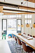 Long wooden table and classic chairs below pendant lamps