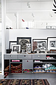 Cushions and kilim rugs stashed in compartments of grey sideboard with black-and-white photographs on top