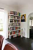 Book shelves, portrait and candlestick next to arched open doorway