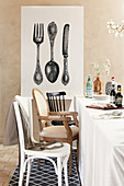 Dining table and various chairs in front of large print of retro cutlery