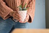 Woman holds mug with blossoming rosemary branches