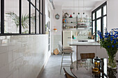 Helle Küche mit weißen Fliesen, Metall-Barhockern und Glastrennwand