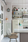 Helle Küche mit Retro-Kühlschrank, Glas-Pendelleuchten und Metallstühlen