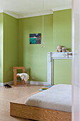 Schlafzimmer mit hellgrünen Wänden und minimalistischem Holz-Design