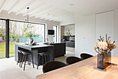 Modern kitchen with large island, bar stools and adjoining wooden dining table