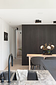 Moderne Küche mit Marmorarbeitsplatte und Essbereich mit dunkler Holzwand