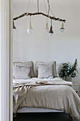 Pendant lights on a branch above the bed in the simple bedroom