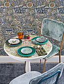 Gedeckter Tisch mit geblümter Platte vor Vintage Blumentapete