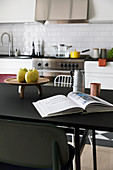 Open book on black dining table in kitchen