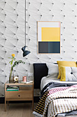 Bild mit Farbflächen an grafisch gemusterter Tapete im Schlafzimmer