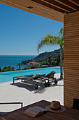 Blick von überdachter Terrasse auf den Swimming Pool mit Meerblick