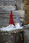 Gestrickte Wichtel als Winterdeko auf rustikalem Holz mit Schnee