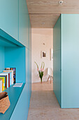Wohnraum mit türkisfarbenen Einbauschränken und Durchgang zum Esszimmer
