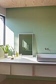 Modernes Badezimmer mit hellgrüner Wand und weißem Waschbecken