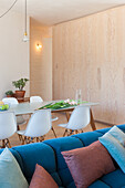 Dining area with white table, chairs and blue sofa with colored pillows