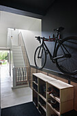 Bicycle on black wall above shoe rack in hallway