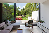 Modern living room with minimalist design, glass front and view of the garden