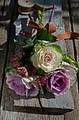 Autumnal arrangement of ornamental cabbages and chrysanthemums with brown ribbon