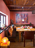 Set table in rustic dining room with corner bench and red walls