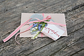 Greetings card decorated with ribbon, lily-of-the-valley and forget-me-nots on love-heart