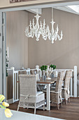 Chandelier above dining table and rattan chairs against beige walls