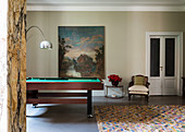 Billiard table, armchair and side table next to painting on wall