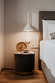 Illuminated bedside table and wall-mounted lamp next to bed with white bed linen