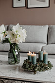 Advent wreath with green candles and white amaryllis in glass vase