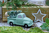 Christmas arrangement with miniature Christmas tree on back of mint-green toy truck