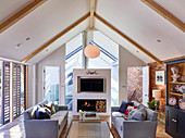 Grey sofas and modern open fireplace in living room below pitched roof