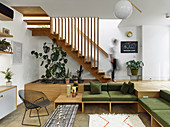 Built-in sofas with green cushions below wooden platform with staircase leading to upper storey