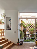 Open glass sliding doors leading to small courtyard garden with foliage plants