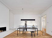 Offener Wohnraum modern minimalistisch eingerichtet mit Küchenzeile, Tisch und Kamin