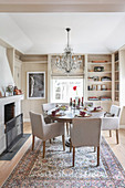 Pale upholstered chairs and round table next to fireplace in dining room