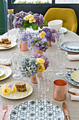 Sommerlich gedeckter Tisch mit gemusterten Tellern und Blumen