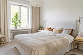Double bed with linen covers and crocheted bedspread in bright bedroom