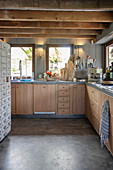 Modern country-house kitchen with wooden cupboards and wood-beamed ceiling
