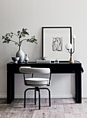 Grey upholstered chair at black console table with graphic decoration