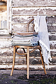 Pile of folded cloths on a coffee house chair in front of the old wooden house