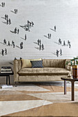 Velvet sofa against wallpaper with pattern of people in beige living room