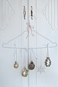 Christmas ornaments and cookie cutters hung on wire hangers as door decorations