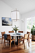 Round dining table with leather chairs, bamboo and cotton lamp above it