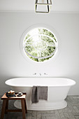 Round swing window above freestanding bathtub