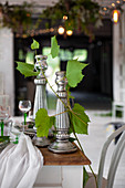 Silver candlesticks and tendrils of leaves on festively set table
