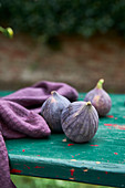Figs and purple linen napkin on turquoise wooden table