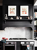 Vintage drawing and silver on black shelf above gas stove